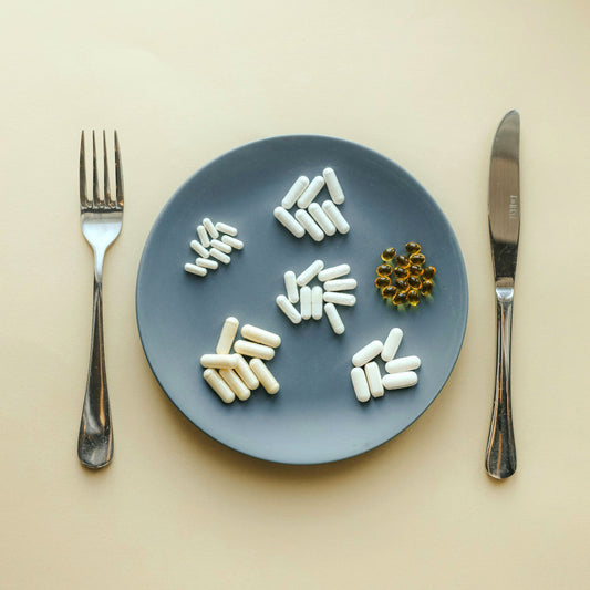 Image shows a plate of different food supplements next to cutlery on a dining table. The photo symbolises how Rebound Recovery combines your different supplements into one, helping to support recovery after social occasions and late nights. 